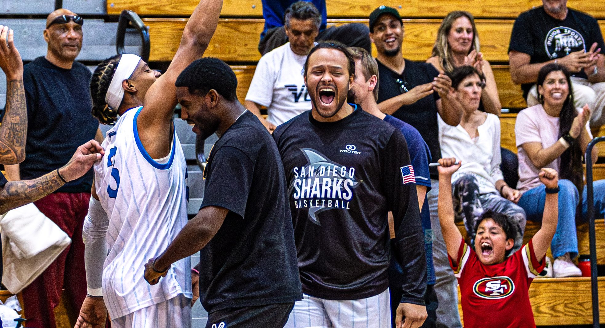Sharks players and fans in the stands celebrating a basket together