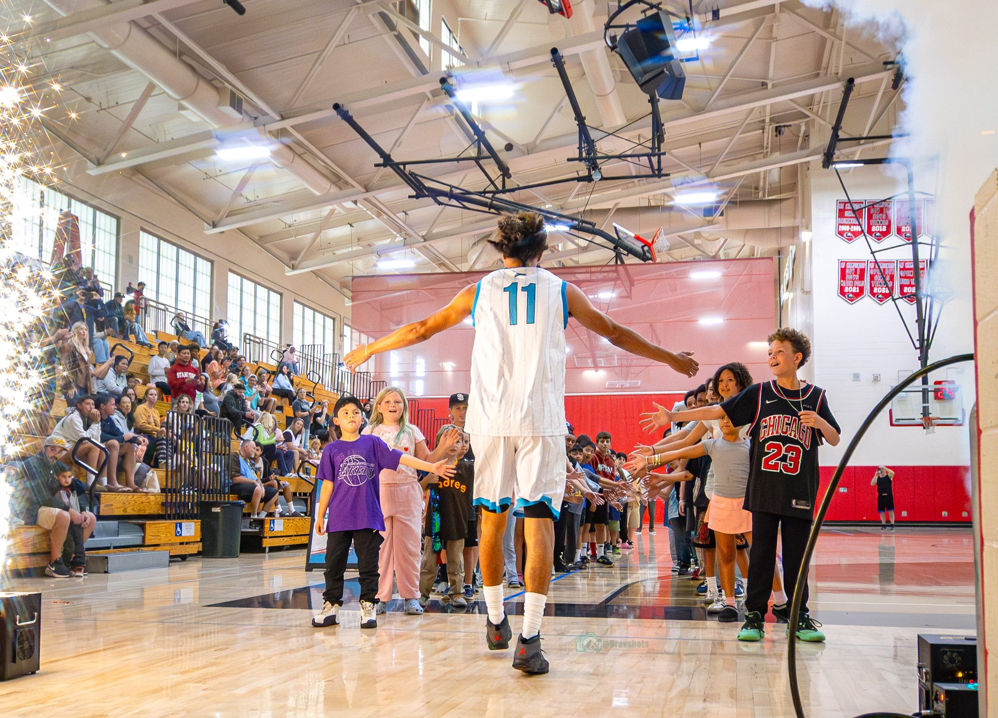 A Sharks player walks through a tunnel of kids trading high fives before tip-off