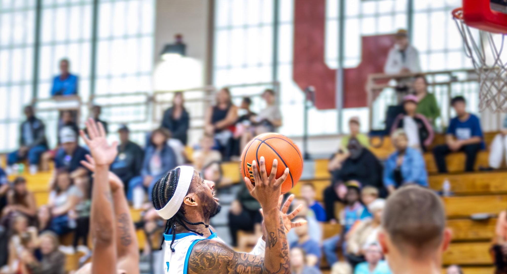 A Sharks player rises for a layup in front of a full bleacher crowd